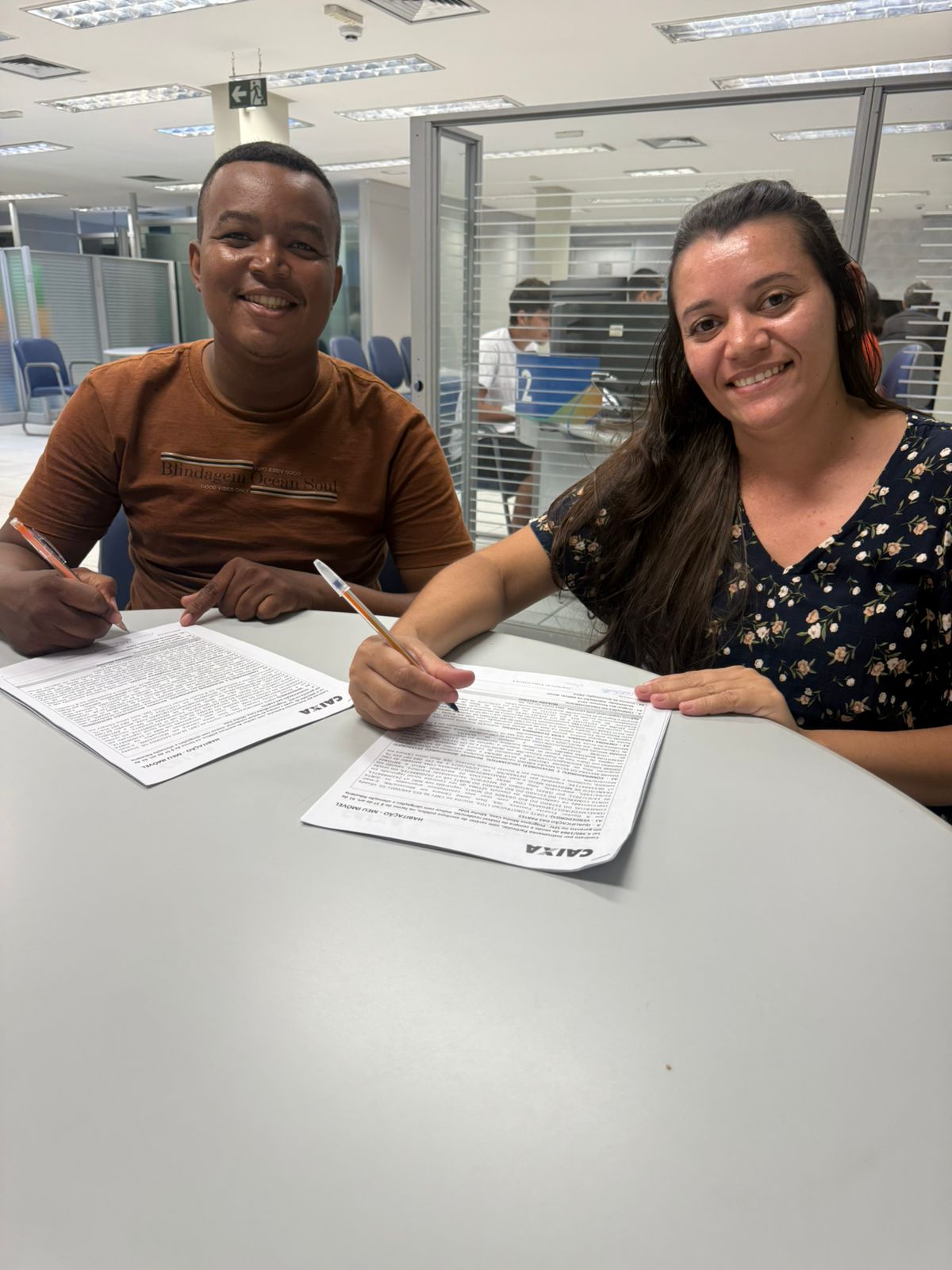 Casal sorridente durante a assinatura do contrato